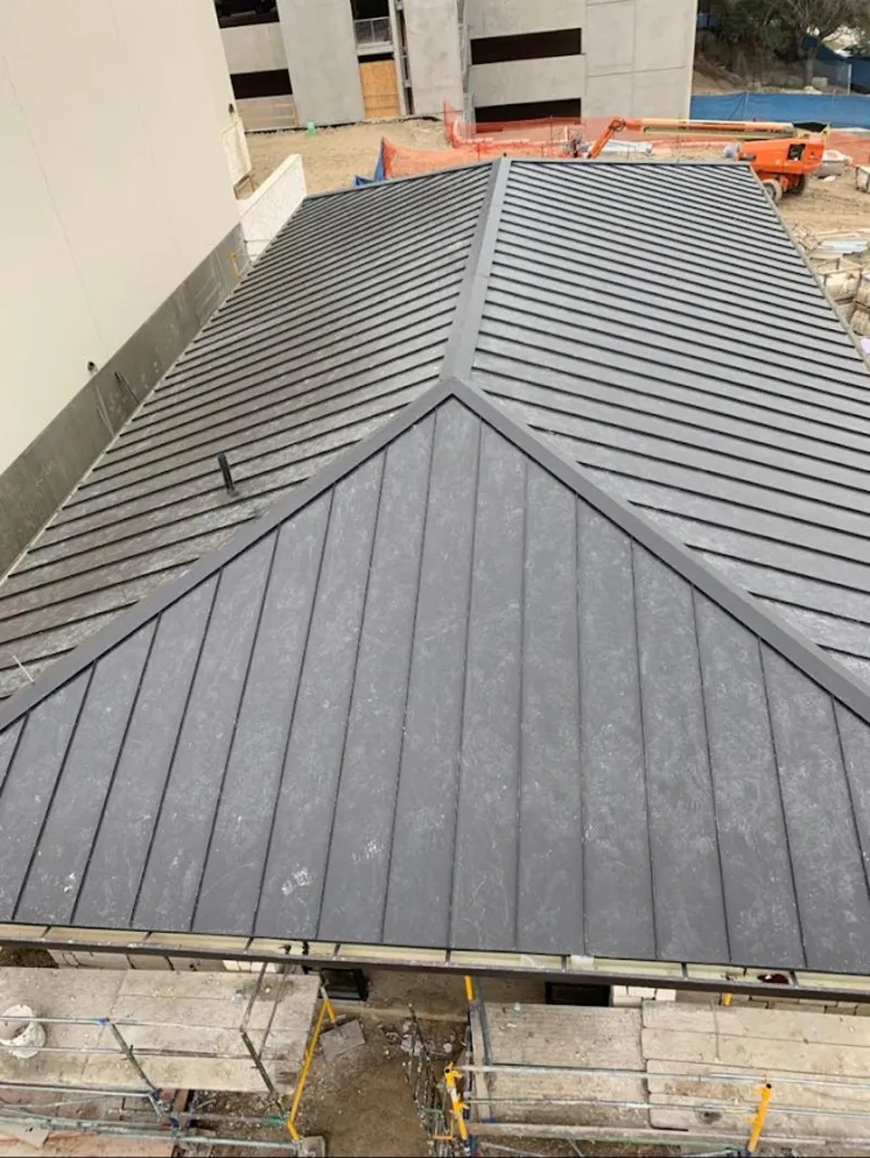Commercial metal roof construction with crane equipment in Vail